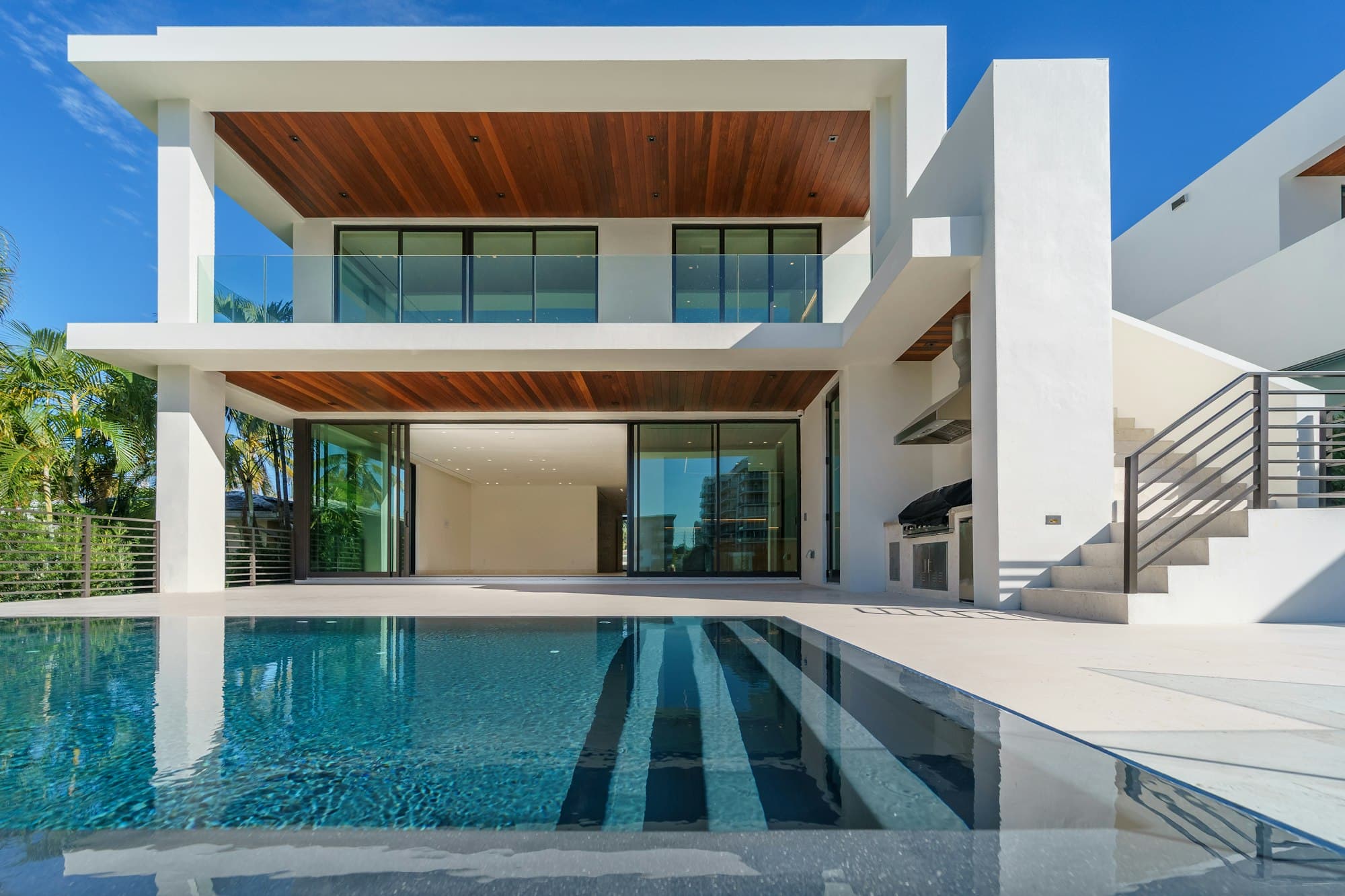 Modern white home with a reflecting pool and palm trees